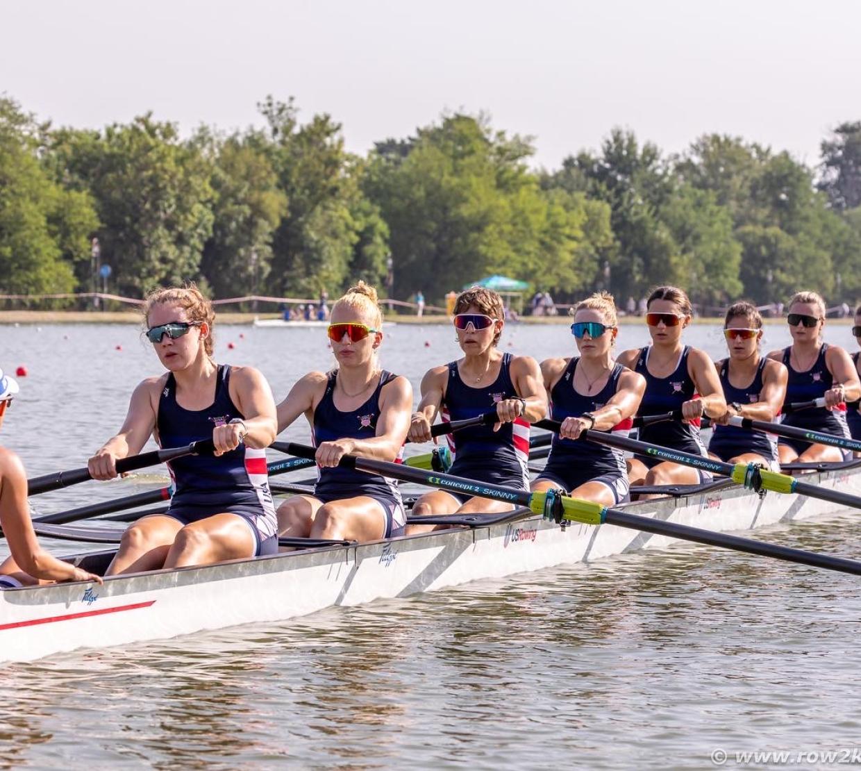 A group of women in a rowing shell during a race.