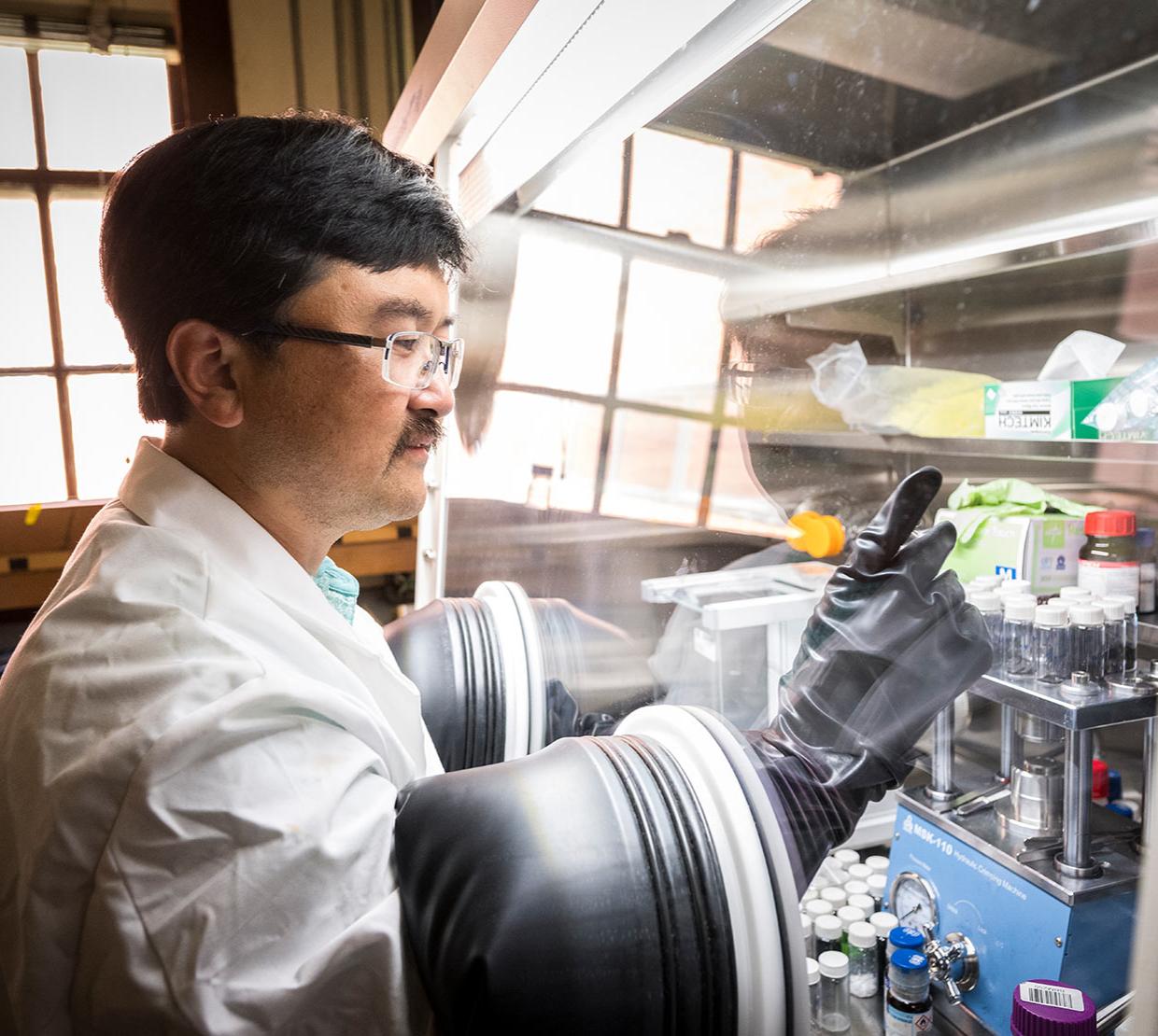 David Ji works in a chemistry lab wearing gloves in a tank.